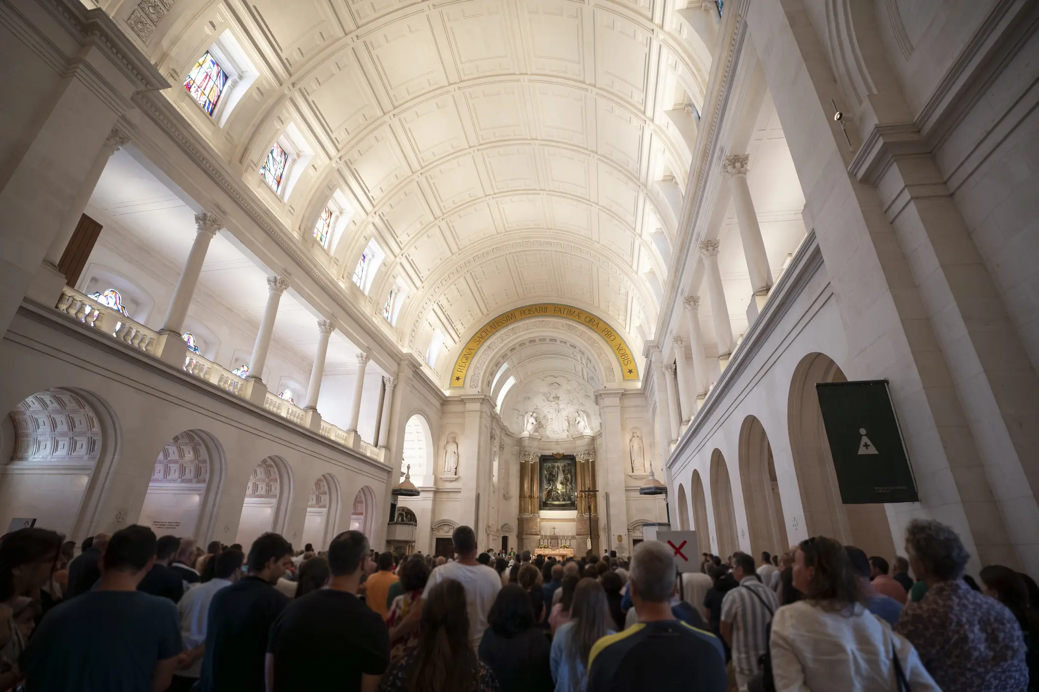 Interior view of a grand church filled with a crowd attending a service.