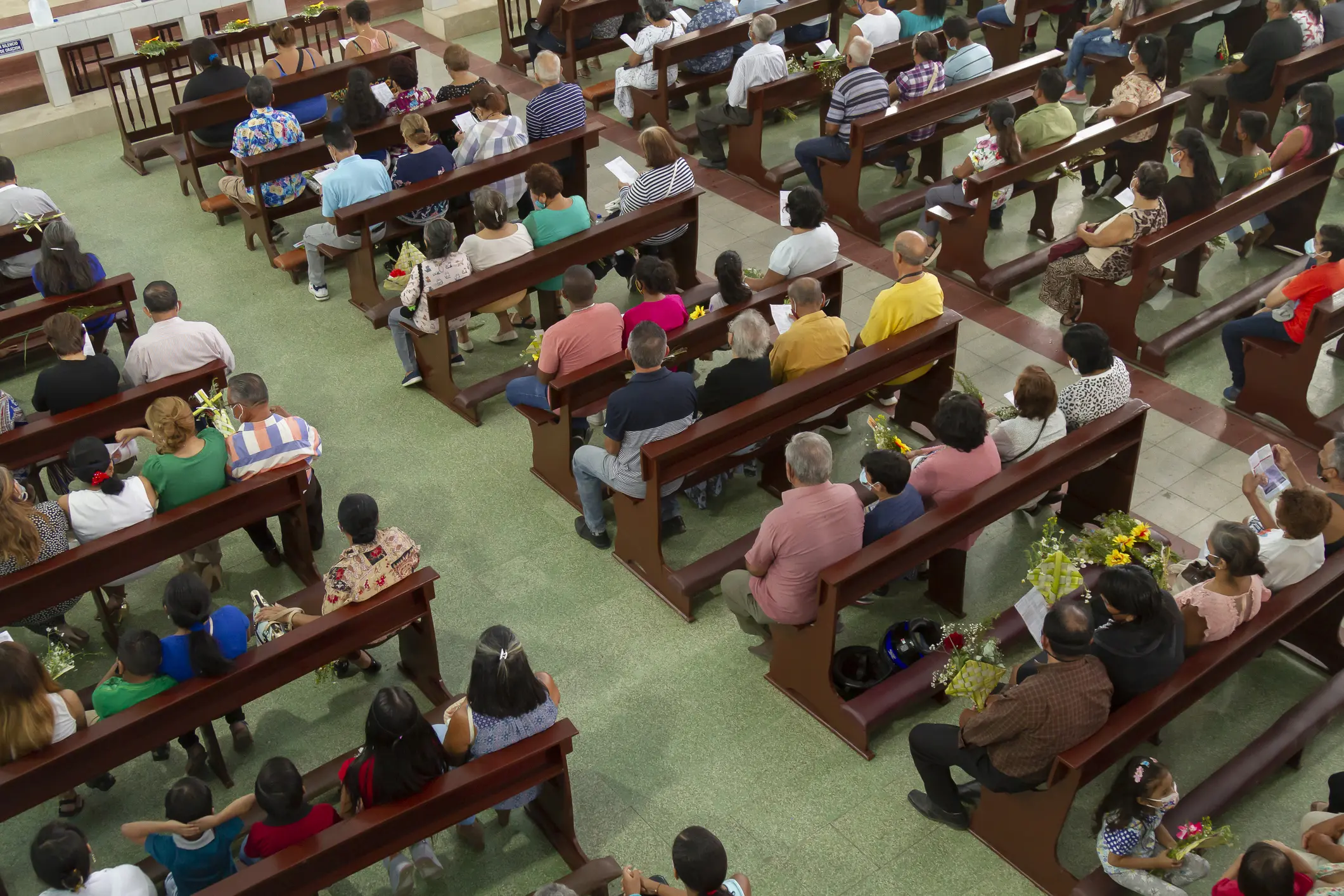 A crowded church with people seated in pews during a service.