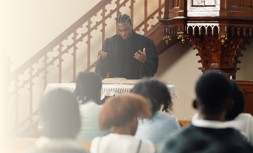 A man passionately preaching in a church to a seated congregation.