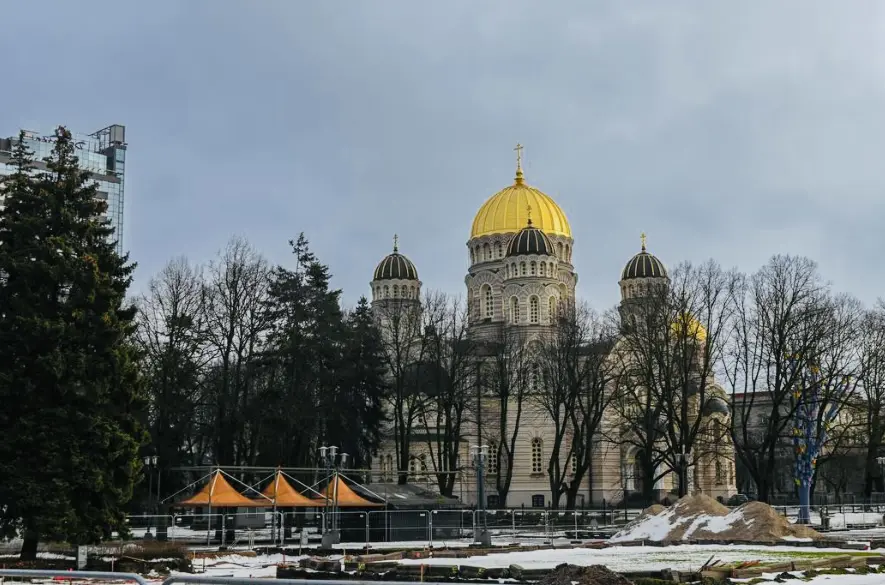 Historic cathedral with golden domes behind trees and tents.